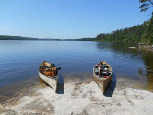 Image of two canoes sitting just on the edge of a lakeside